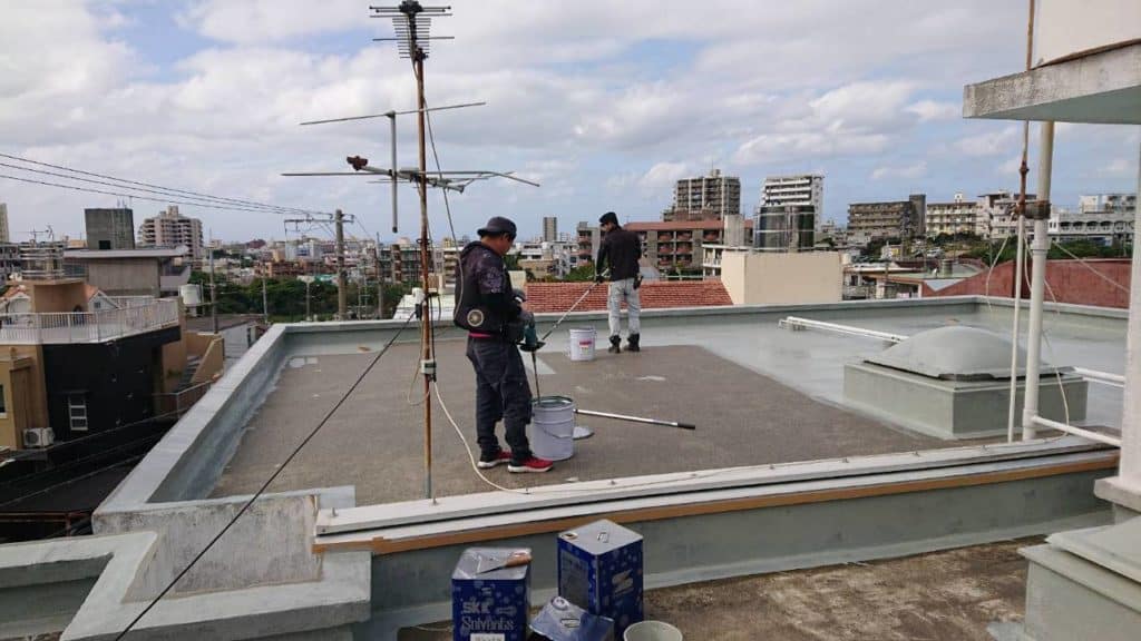 住宅の屋上で防水作業を行う作業員1